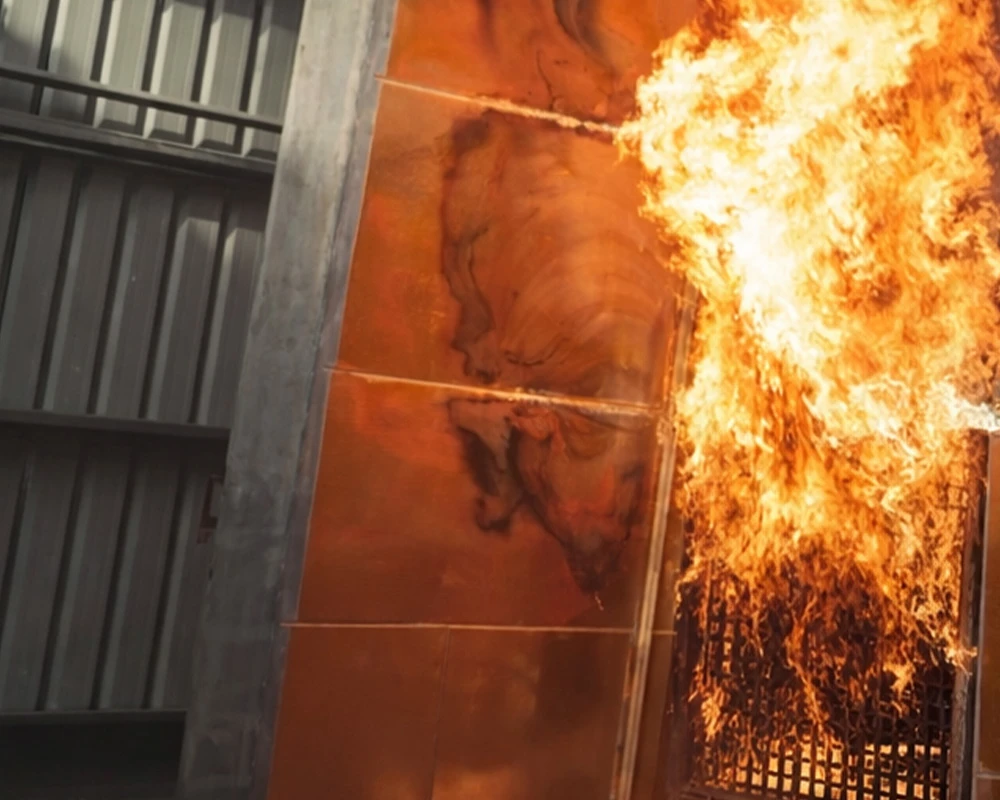 Fire safety test showing flames spreading across a building façade system during controlled cladding performance testing