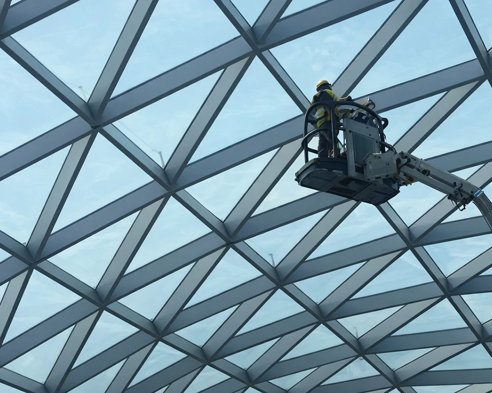Operative using a mobile access platform to inspect or maintain a glazed roof structure with a geometric steel framework